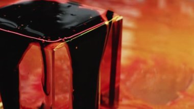 Fluid magic. Creative presentation. Fashion art. Black stream of liquid paint pouring out of golden glassy cube macro shooting.