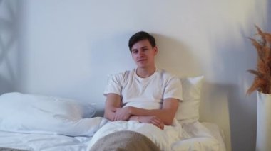 Bed daydreaming. Home rest. Lazy weekend relaxation. Evening leisure. Peaceful pensive man enjoying contemplation alone in bedroom.