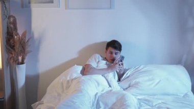Night fear. Scared phone call. Panic attack anxiety. Frightened terrified disturbed guy in bed reporting late home intrusion in dark bedroom.