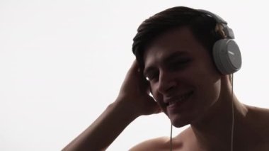 Music inspiration. Summer vibe. Sound technology. Happy smiling shirtless DJ guy enjoying listening to playlist in headphones isolated on white copy space background.
