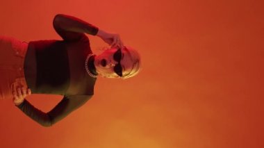 Wow face. Amazing surprise. Exciting news. Shocked fashionable mature woman with open mouth in bright orange neon light copy space vertical.