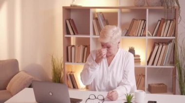 Work fatigue. Eye strain. Old age problem. Tired overworked senior business woman closing laptop at home desk workplace resting on couch.
