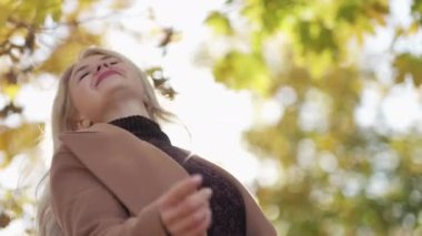 Happy day. Beautiful woman. Enjoying autumn. Pretty excited lady feeling joy playing with hair while walking in sunny park slow motion.