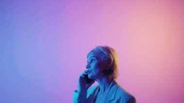 Mobile call. Phone consulting. Connection advertisement. Serious mature woman talking on smartphone conversation in colorful neon light studio copy space.