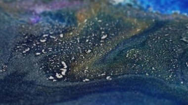 Ink floating. Glitter fluid wave. Shimmering sea foam. Defocused blue gold color wet paint spreading grain texture abstract art background.