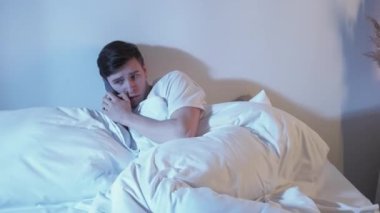 Disturbing phone call. Night stress. Mobile anxiety. Paranoia attack. Scared afraid nervous guy in bed listening horror story in bed
