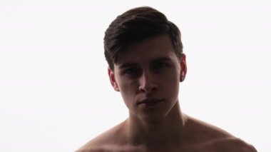 Shirtless man face. Skin care. Grooming cosmetology. Portrait of confident handsome brunet guy isolated on white copy space background.