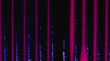 Nail polish palette. Fluid magic. Creative art. Pink liquid stream of paint floating in dark violet rows in macro shooting.