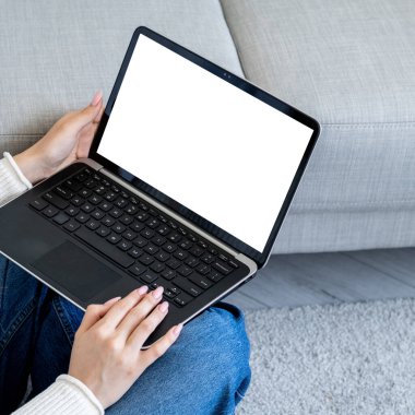 Digital mockup. Distance work. Online technology. Unrecognizable woman typing laptop blank screen holding knees sitting floor room interior.