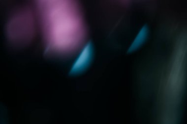 Blur light leak. Lens flare. Bokeh rays. Defocused purple blue color flecks glow on dark night black abstract copy space background.