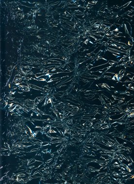 Crumpled foil texture. Wrinkled noise. Crinkled film wrap. Blue orange white flare reflection on used rough dark abstract illustration background.