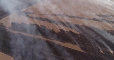 Arson. Agriulture competition. Burning crops. Aerial shot of smoke rising above fields