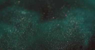 Particles background. Bokeh glitter flow. Sparkles in water. Defocused teal blue golden color grain flare motion on dark vertical abstract texture. Shot on RED Cinema camera.
