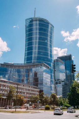 Warsaw, Poland - June 27, 2022: Neomodern architecture. Business center. Downtown city. Street road with high glassy building complex Warsaw Spire in sunny daylight.
