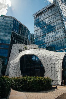 Warsaw, Poland - June 22, 2022: Unusual architecture. Futuristic style. Modern city. Space looking cafe Baraboo on high glassy building background in sunny daylight.