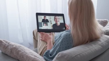 Çevrimiçi toplantı. Sıradan bir kadın. Görüntülü arama. Rahat bayan rahat koltukta oturup, aydınlatma odasının içindeki tablet bilgisayarda sanal konferans veriyor..