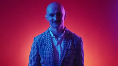 Mutlu bir hayat. Neşeli adam. Neon ışıklı portre. Kendine güveni tam gülümseyen adam kırmızı sarı arkaplan hareketinde poz veriyor..