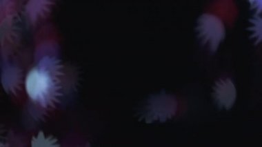Bokeh parıltısı örtüsü. Bulanık çiçek deseni. Renk parlaklığı. Karanlık, siyah dekoratif, soyut kopya alanı üzerinde odaklanmış kırmızı ışık parlaması hareketi.