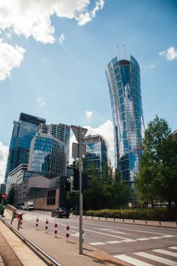 Varşova, Polonya - 22 Haziran 2022: Neomodern mimari. İş merkezi. Şehir merkezinde. Yüksek camlı binalı sokak yolu güneşli gün ışığında Varşova Spire.