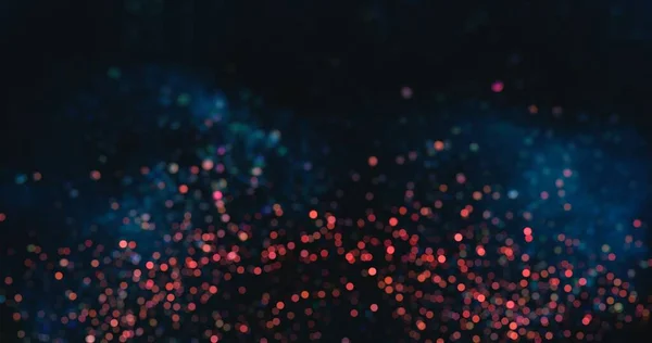 Bokeh sparks. Particles background. Firework flare. Defocused blue red color blur glowing circles texture on dark black abstract wallpaper.