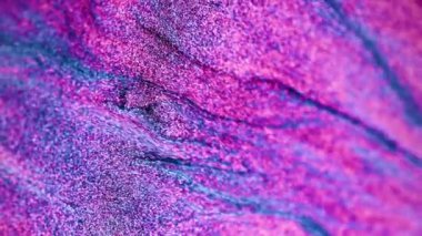 Dikey video. Parıldayan sıvı akışı. Parıldayan dalga. Renkli kum. Neon mavisi pembe parlak parçacıklar holografik soyut mermer desenli arkaplan. RED Sinema Kamerasında Çekim.