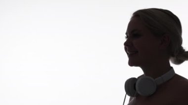 Gadget insanları. Ses cihazı. Modern teknoloji. Beyaz fotokopi arkaplanında izole edilmiş kulaklıklı gülümseyen kız yüzünün karanlık profil silueti.