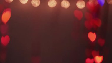 Romantik bir geçmiş. Sevgililer Günü. Işık süslemesi. Sarı iplik neon kırmızı renk bokeh kalpler sönük koyu soyut dokuda parlar.