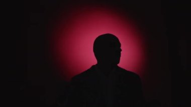 Suçluyu yakala. Tutuklu adam. Polis teftişi. Korkmuş kayıp adam elini kaldırıyor. Kırmızı, neon ışıklı arka planda protesto yapıyor..