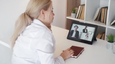 Sıkıcı video. Yorgun bir kadın. İnternetteki konferans. Tükenmiş bir kadın, aydınlatma odasının iç tarafındaki tablet bilgisayarda sanal toplantı yaparken uyuyakalıyor..