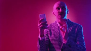 Çevrimiçi bağlantı. Mutlu adam. Mobil teknoloji. Akıllı telefondan konuşan etkileyici bir adam harika haberler hakkında neon açık pembe arka plan.