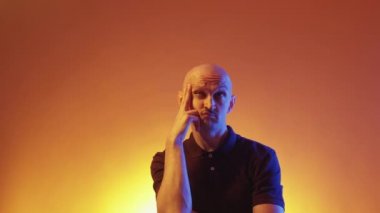 Eureka jesti. Kafası karışmış bir adam. Karar ver. Sarı turuncu ışıklı arka planda mutluluk parmağını ifade eden sıradan bir adam..