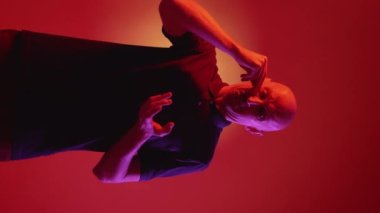 Dikey video. Aptal keder. Ağlayan adam. Hayal kırıklığına uğramış dramatik adam kırmızı neon ışıklı arka planda avuç içinde ağlıyor..