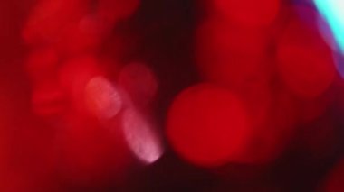 Işık parlaması üstüste biniyor. Neon bokeh parıltısı. Görüntü kıvılcımları parıldıyor. Karanlık soyut arkaplanda odaklanmış kırmızı renkli yuvarlak benekler hareketi.