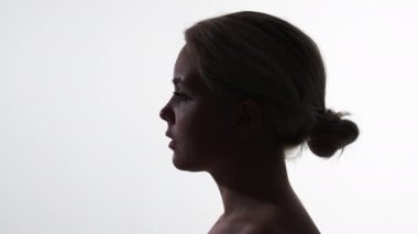 Duygusuz surat. Yalnızlık melankolisi. Boş bakış. Kederli, sakin, ilgisiz kadın siluetinin karanlık profili beyaz kopya alanı arka planında izole edilmiş..