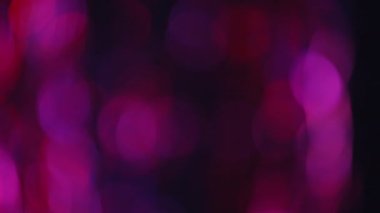 Bokeh parıltısı örtüsü. Bulanık neon halkalar. Gece şehir ışıkları. Aydınlanma şenliği. Siyah soyut arkaplan üzerinde odaklanmış floresan pembe renkli işaret fişeği hareketi.