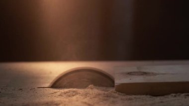 Doğramacılık işi. Marangozluk yapımı. Ahşap işçiliği. Eldivenli zanaatkar elleri tahta kesiyor, koyu bulanık alanda testere bıçağı kullanıyor, talaşla kaplı..