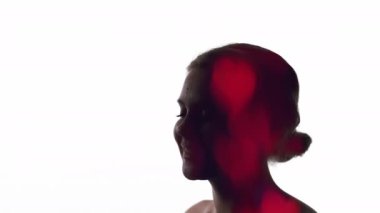 Aşk ilhamı. Romantik bir hava. Manevi güzellik. Beyaz fotokopi arkaplanında izole edilmiş kırmızı neon bokeh kalplerle mutlu, gevşemiş kadın yüzünün çift pozlu silüeti..