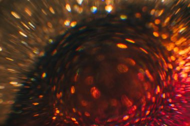 Bulanık kırmızı ışıklar. Aydınlatılmış girdap arka planı. Karanlık soyut sanat. Renkli mercek parıltısı.