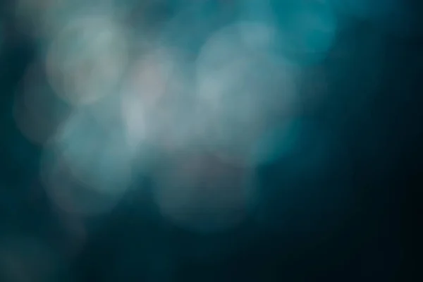 Bokeh light overlay. Lens flare texture. Blur circles glare. Defocused white pink teal blue color round flecks on dark abstract copy space background.