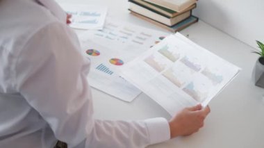 Finansal rapor. Kafası karışmış kadın. Belge araştırması. Tanımlanamayan bir bayan, ofis içi aydınlatma odasındaki bilgilerle kağıtları inceliyor..