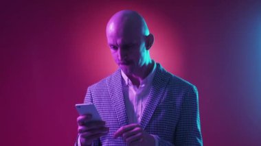 Etkileyici bir haber. Kazanan adam. Mobil teknoloji. Mutlu adam akıllı telefonu kaydırıyor, neon ışıklı pembe arka planda kutlama yapıyor..