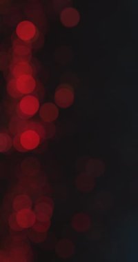 Bokeh parıltısı örtüsü. Bulanık daire dokusu. Neşeli bir ışık parlaması. Odaklanmamış kırmızı renkli yuvarlak baloncuklar koyu siyah soyut arkaplan. Dikey video. RED Sinema Kamerasında Çekim.
