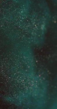 Parçacık arkaplanı. Bokeh sim akışı. Suda parlıyor. Odaklanmamış gök mavisi altın rengi tahıl alevi hareket ettiren koyu soyut doku. Dikey video. RED Sinema Kamerasında Çekim.