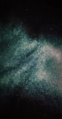 Parlak toz girdabı. Parçacık arkaplanı. Bokeh hafif dokusu. Odaklanmamış yeşil turuncu baloncuklar koyu siyah soyut örtüye sıçrıyor. Dikey video. RED Sinema Kamerasında Çekim.