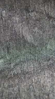Vertical video. Shimmering background. Glitter noise. Shiny particles drip. Defocused black white green sparkling grain motion abstract texture. Shot on RED Cinema camera.
