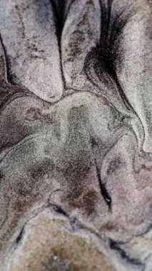 Dikey video. Parıldayan sıvı akışı. Işıltılı doku. Siyah bej beyaz parıldayan parçacıklar soyut mermer arkaplan hareketi. RED Sinema Kamerasında Çekim.