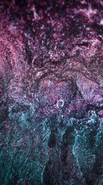 Vertical video. Particles background. Glitter fluid. Sequin flow. Defocused blue pink color holographic shiny ink mix abstract grain texture. Shot on RED Cinema camera.