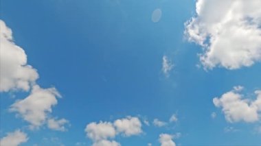 Gökyüzü özgürlüğü. Güneşli bir hava. Doğa güzelliği. Açık mavi gökyüzü, beyaz çalılı bulutlar yüksekten uçuyor, hızlı hareket lensleri parlıyor..