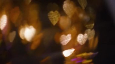 Romantik bokeh ışığı. Sevgililer Günü. Tatil dekoratif kaplama. Odaklanmamış parlak altın renkli kalpler koyu soyut arka planda parıldıyor.