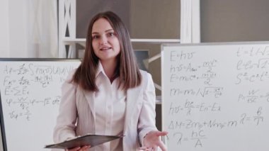 Çevrimiçi öğretmenlik. Uzaktan ders. Uzaktan eğitim. Sanal sınıfta beyaz tahtada formülleri açıklayan kendine güvenen bir kadın. Uzun video çekimi.